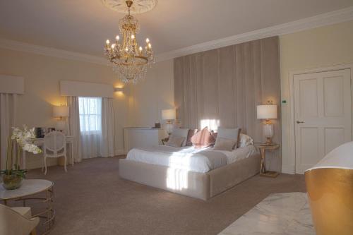 a bedroom with a large white bed and a chandelier at Winstanley House in Leicester