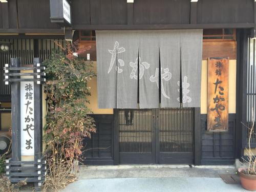 a building with a gate with writing on it at Ryokan Takayama in Takayama