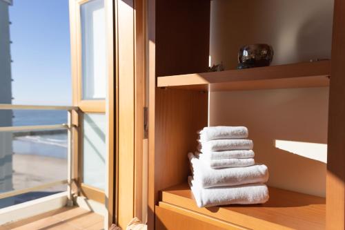 a pile of towels sitting on a shelf next to a window at Ofir Beach Flat in Esposende