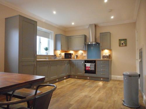 a kitchen with gray cabinets and a wooden table and a tableablish at East Cottage at Parbroath Farm in Cupar