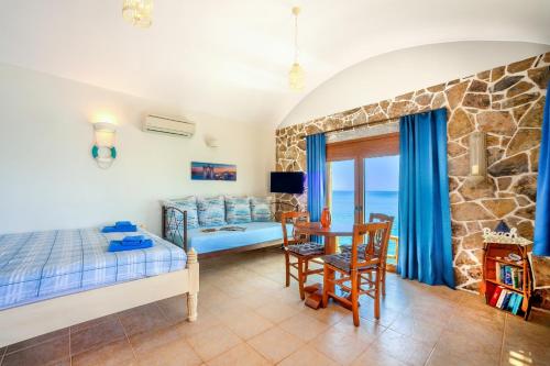 a bedroom with a bed and a desk and a table at Plaka Beach Cottages in Pláka