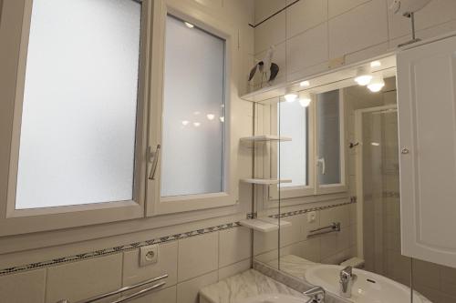 La salle de bains blanche est pourvue d'un lavabo et d'un miroir. dans l'établissement le FAMILY LODGE 2 chambres 4 personnes classe 3 etoiles, à Annecy