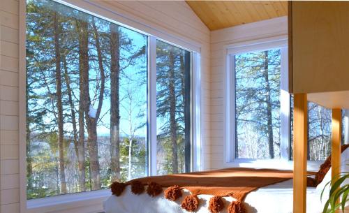 1 dormitorio con ventana grande y cama. en Charlevoix expérience thermale en pleine nature - Suites Nature Charlevoix - Suite #1, en Les Éboulements