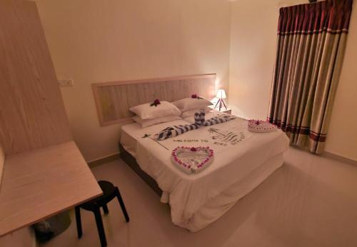 a bedroom with a bed with white sheets and flowers on it at Bird Beak Beach in Omadhoo