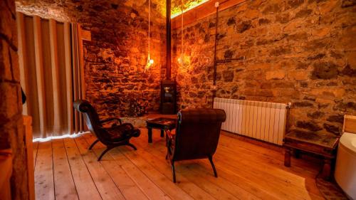 a room with two chairs and a table and a brick wall at Hotel Xaluca Spa Aguelmame Sidi Ali in Aguelman