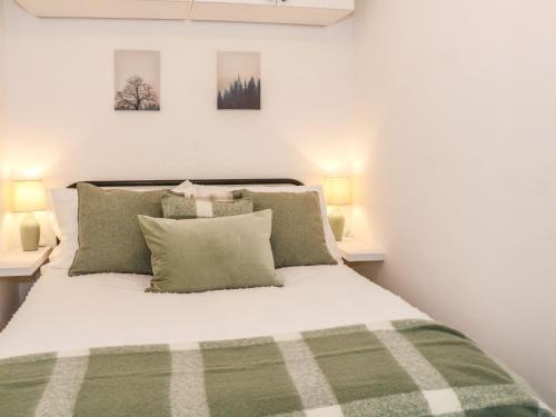 een slaapkamer met een groen en wit bed met 2 lampen bij Hope Cottage in Hambleton