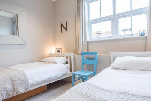 a bedroom with two beds and a blue chair at 3 St Nicholas Court, Aldeburgh in Aldeburgh