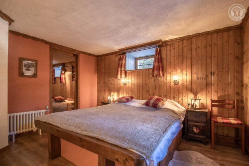 ein Schlafzimmer mit einem Bett in einem Zimmer mit Holzwänden in der Unterkunft Gite cosy en montagne avec vue et piscine in Marthod