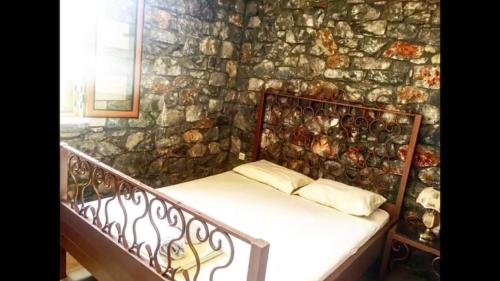 a bedroom with a stone wall with a bed at Sunshine Villa in Stoupa