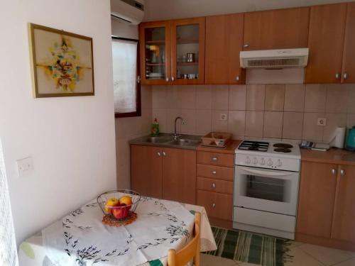 a kitchen with a table with a bowl of fruit on it at Apartments Martinac in Sukošan