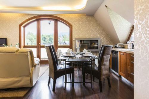 a kitchen with a table and chairs and a kitchen with a window at Apartament De Lux Cicha Woda in Zakopane