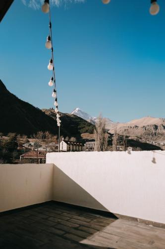 a balcony with a white wall and a view of the mountains at Paramount Kazbegi in Stepantsminda