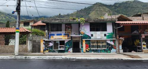 a building with paintings on it on the side of a street at La Casa del Pan de Yuca Baños in Baños