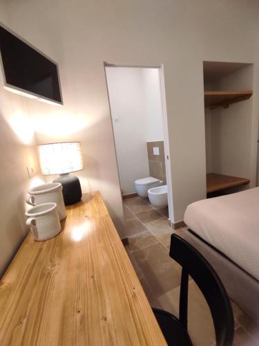 1 dormitorio con cama, mesa y baño en La Maison, en Trani