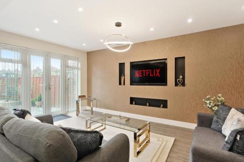 a living room with a couch and a tv on the wall at Luxurious 4 Bed House, Solihull, NEC, Airport, Business & Leisure Stays - Wisteria House in Solihull