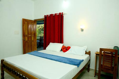 a bedroom with a bed with a red curtain at THEKKADY HOMES in Thekkady