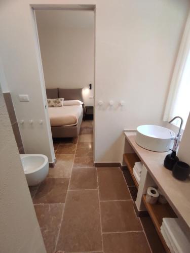 a bathroom with two sinks and a toilet and a bed at La Maison in Trani