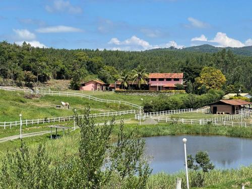 una granja con una valla blanca y un río en Fazenda Santa Amalia, 