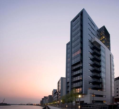 a tall building with a sunset in the background at Water view harbour in Glasgow