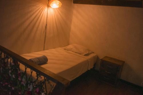 a small bedroom with a bed and a light at Hostal Españolete in Santa Marta