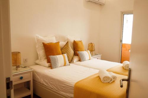 1 dormitorio con 1 cama con almohadas amarillas y blancas en So Sweet Center of Faro Flat, en Faro