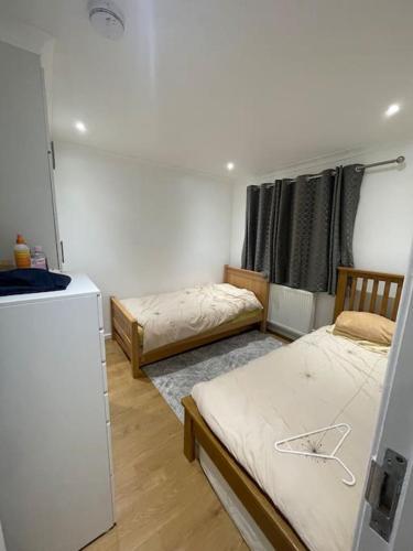 a room with two twin beds and a refrigerator at 2 Bedroom House - West London in Northolt