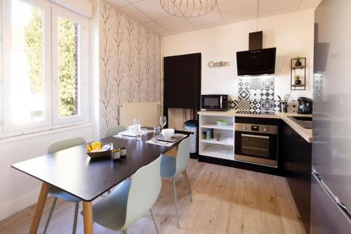 eine Küche und ein Esszimmer mit Tisch und Stühlen in der Unterkunft Le Citadin E - Entièrement Équipé - Centre-Ville Gare in Montluçon