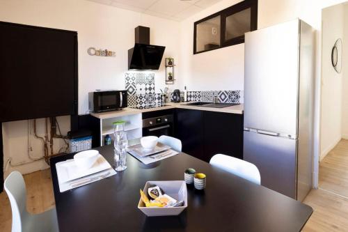 Il comprend une cuisine équipée d'une table noire et d'un réfrigérateur. dans l'établissement Le Citadin E - Entièrement Équipé - Centre-Ville Gare, à Montluçon