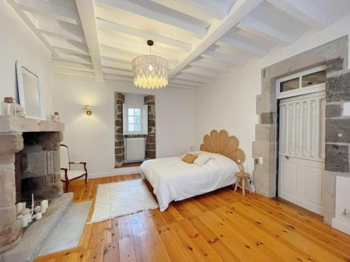 a white bedroom with a bed and a fireplace at Logis du Chandelier in Le Puy en Velay