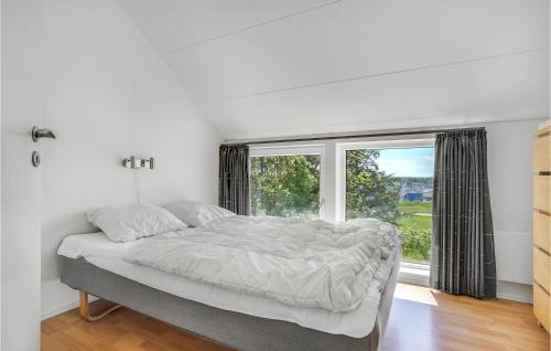 a bedroom with a large bed and a window at Awesome Home In Ebeltoft With 6 Bedrooms, Private Swimming Pool And Indoor Swimming Pool in Ebeltoft