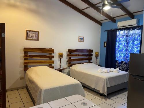 two beds in a room with blue walls at Cabinas El Colibri in Carrillo