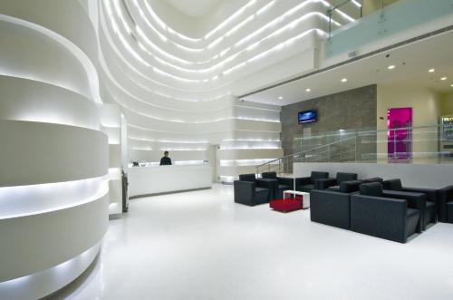 a lobby with black chairs and a person at a counter at Keys Select by Lemon Tree Hotels, Thiruvananthapuram in Trivandrum