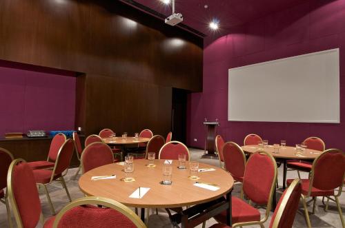 a conference room with tables and chairs and a white screen at Keys Select by Lemon Tree Hotels, Thiruvananthapuram in Trivandrum