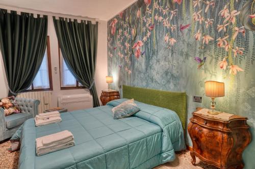 a bedroom with a blue bed and a floral wallpaper at Biennale Venice Charme Apartment in Venice