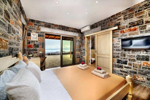 a bedroom with a brick wall and a tv at Falcon Villa in Chavgas