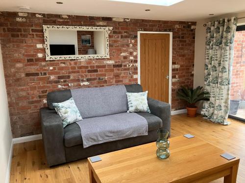 a living room with a couch and a brick wall at Honeyberry Cottage -PART OF ALTON COTTAGES in Alton