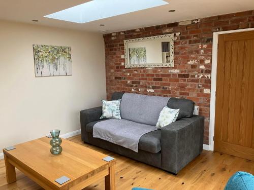 a living room with a couch and a brick wall at Honeyberry Cottage -PART OF ALTON COTTAGES in Alton