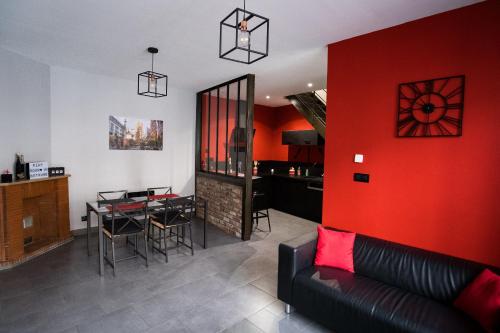 sala de estar con sofá y pared roja en La Maison Coquine en Béthune