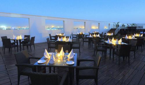 a restaurant with tables and chairs on a roof at Hotel Marigold Jaipur in Jaipur