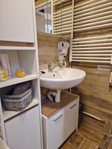 a bathroom with a white sink and wooden walls at Veludo Apartments in Banská Bystrica