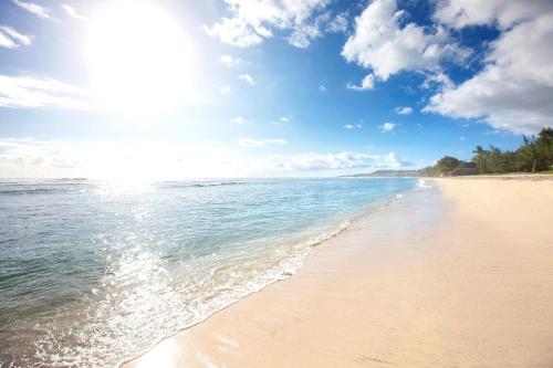 a beach with the sun shining on the water at Hotel Le Recif, Ile de la Reunion in Saint-Gilles les Bains