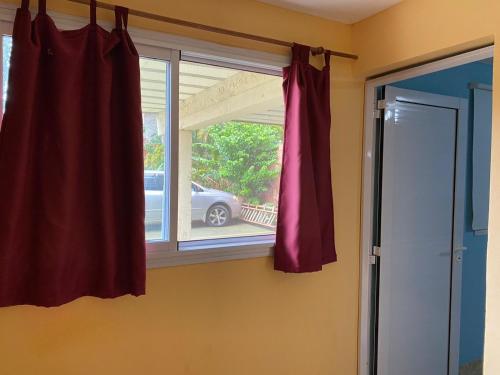a window with a red curtain next to a door at Hotel Itavera in Puerto Iguazú