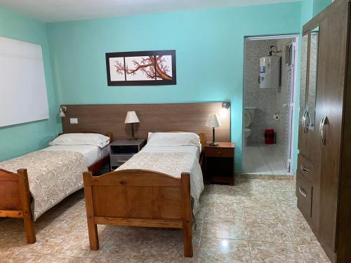 a bedroom with two beds and a blue wall at Hotel Itavera in Puerto Iguazú
