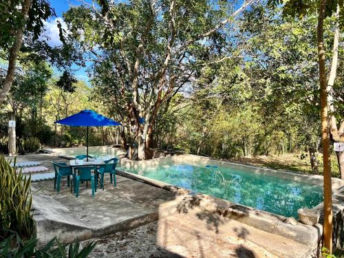 a table with an umbrella next to a swimming pool at El Encanto - Hotel Boutique in Chichén-Itzá