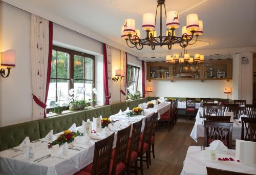 una sala da pranzo con tavoli e sedie bianchi di Landgasthof Rechenwirt a Elsbethen