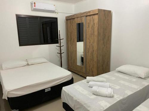 イジュイーにあるApart-Hotel Ijuíのベッドルーム1室(ベッド2台、木製キャビネット付)