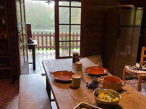 une table en bois avec deux assiettes de nourriture dans l'établissement Chalet nature avec étang, terrasse et pêche No Kill - 2 chambres - FR-1-410-383, à Dehault