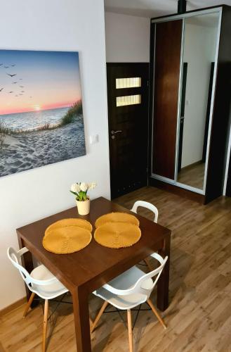 a dining room with a wooden table and white chairs at ATRIUM Sarbinowo Na Fali in Sarbinowo