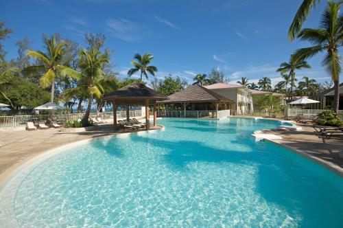 a large swimming pool in a resort with palm trees at Hotel Le Recif, Ile de la Reunion in Saint-Gilles les Bains