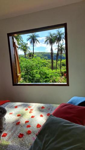 Schlafzimmer mit einem Fenster mit Blick auf Palmen in der Unterkunft Pousada Sempre Luz in Santana do Riacho